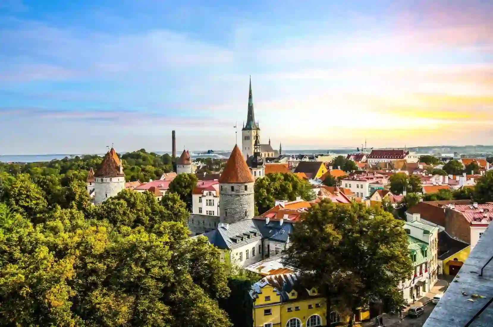 Medieval towers and colourful rooftops in the old town of Tallinn, with a church spire in the background