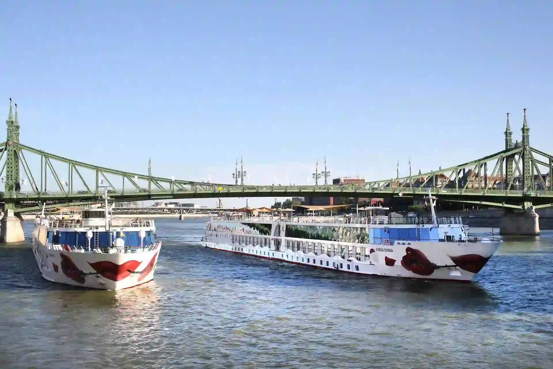 The A-ROSA DONNA river cruise ship passing beneath historic bridges over the Danube River in Budapest